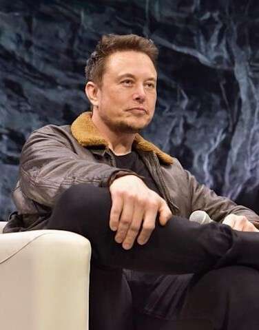 ELON MUSK Sitting in a chair with legs crossed
